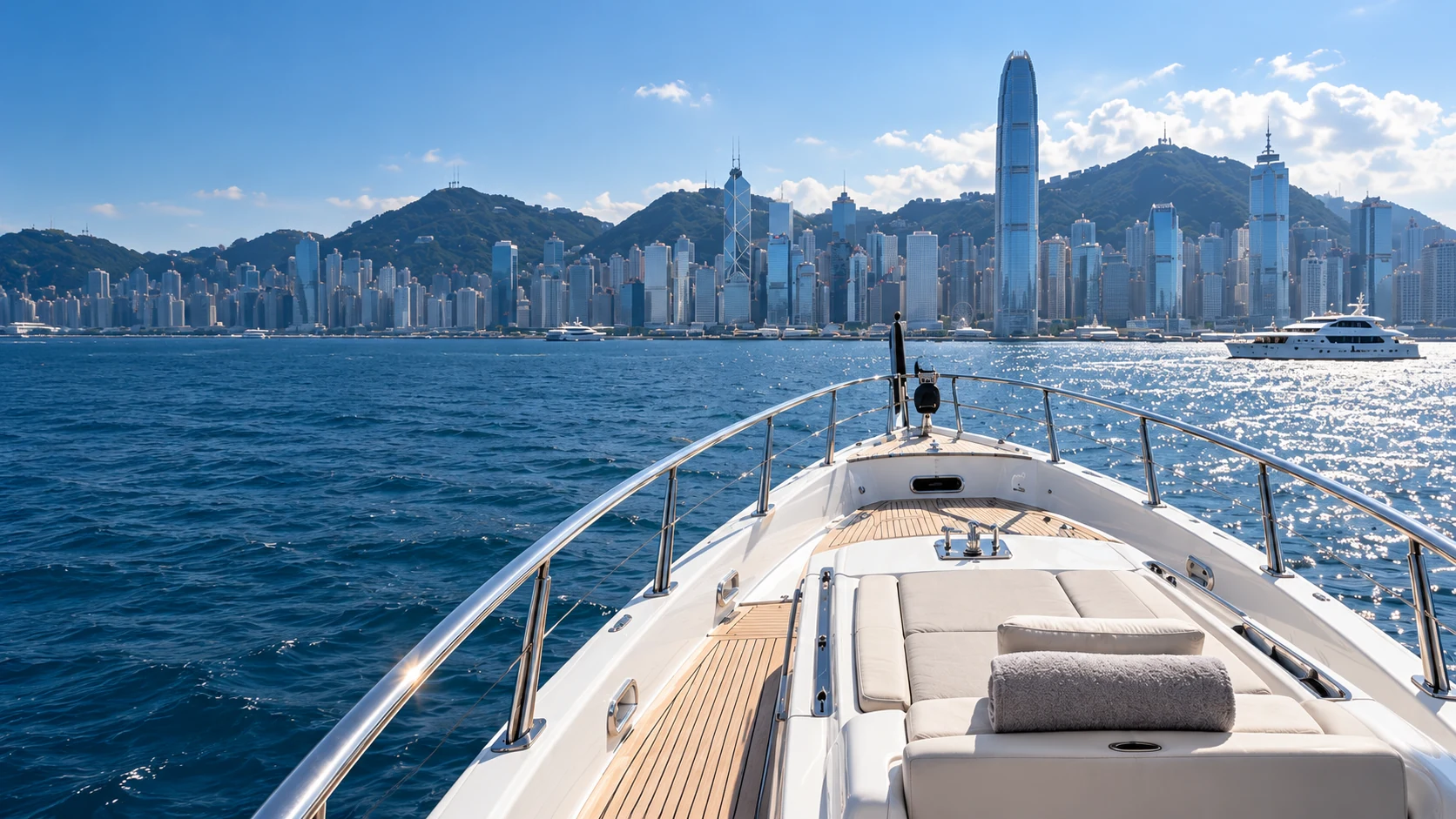 A yacht’s bow facing the Hong Kong skyline across Victoria Harbour.